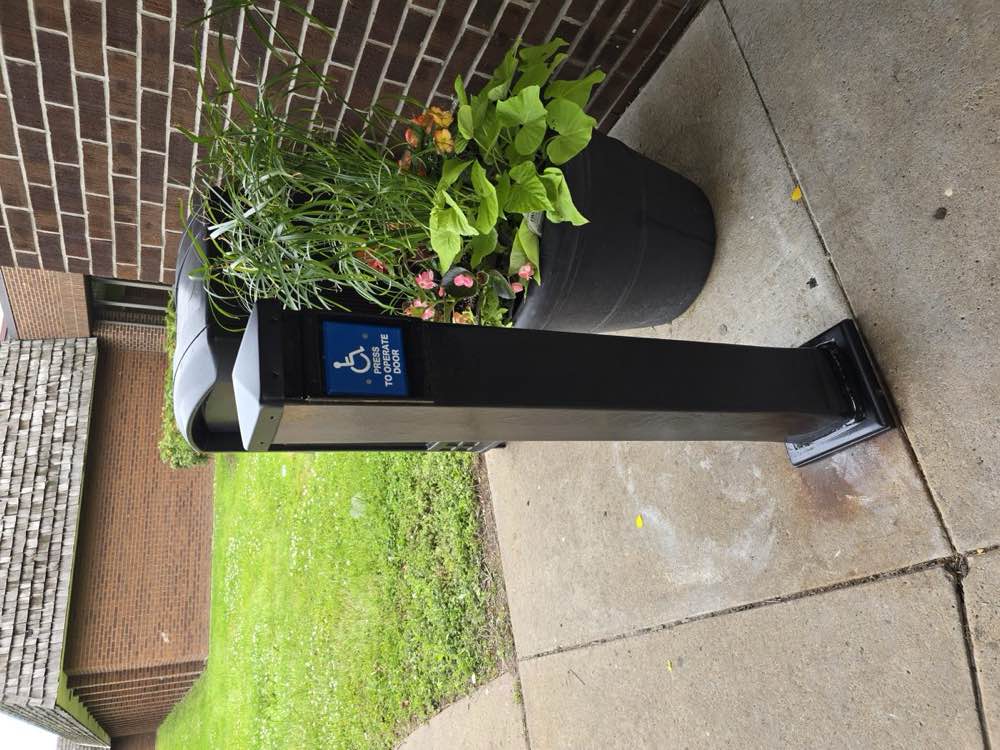 The same entrance post renewed, with a clean and legible accessibility plate