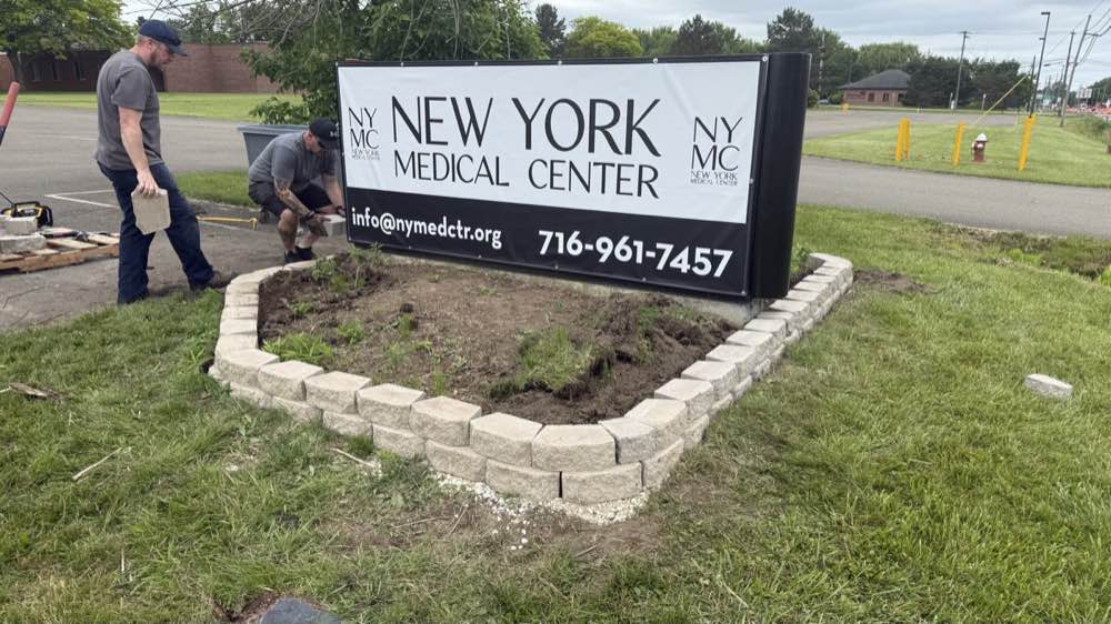 Crew building the stone surround for the roadside sign